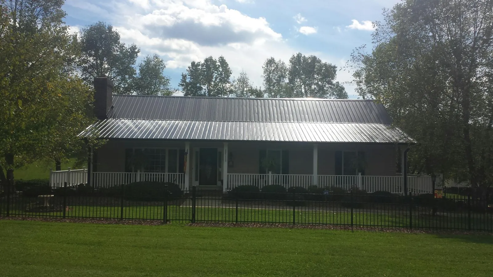 Gray metal roof on a brick ranch with a full width front porch — Gutter Guard Installation work by our crew in Broadview
