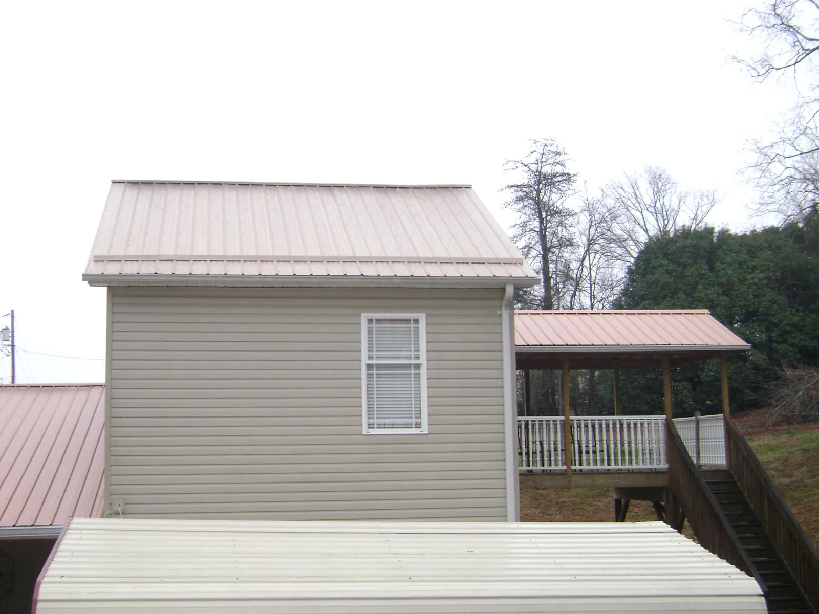 Tan metal roofs on a two story addition and attached porch, from a Roof Replacement job in Broadview